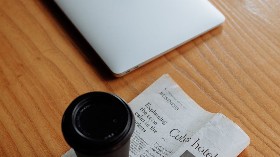 Workspace with laptop, coffee and newspaper